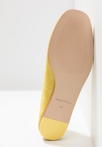 Semelle en suède jaune avec une base en caoutchouc beige, présentant des rainures texturées et le logo embossé "Marc O'Polo" avec la taille "4.5."