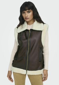 Bruine nepleren vest met een crèmekleurige nep-shearling kraag en zoom, frontale ritssluiting en zijzakken, met verstelbare details aan de zijkanten.