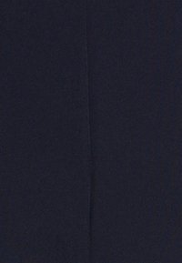 Närbild av mörk marinblått tyg med en fin söm som löper vertikalt genom mitten.