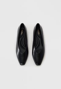 Chaussures noires en cuir à enfiler avec un bout pointu, texture lisse et un design décolleté, dotées d'une semelle intérieure douce et d'un intérieur de marque.