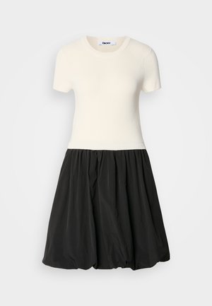 Top ivory cu dungi, cu mânecă scurtă și fustă neagră tip balon. Rochia are un decolteu ajustat și o partea inferioară voluminoasă, texturată.