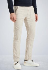 Beige katoenen broek met een slim fit, met voorzakken en verticale stikdetails, gecombineerd met witte sneakers.