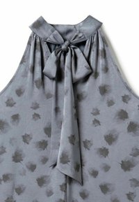 Sivi halter top od glatkog materijala, s mašnom na izrezu vrata i uzorkom tamnijih mrlja u obliku listova.