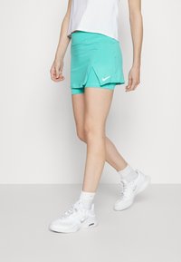 Turkoosi urheiluhame, jossa on halkiosuunnittelu. Valmistettu kevyestä ja hengittävästä materiaalista. Valkoinen Nike-tekijälogo edessä.