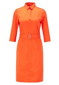 Pomarańczowa sukienka koszulowa z kołnierzykiem, rękawami o długości trzy czwarte i wcięciem w talii z prostokątną klamrą pasa. Gładka tekstura.