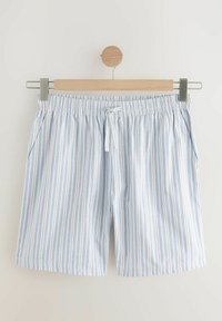 Shorts rayés bleu clair et blanc avec un waistband élastique et des poches avant, fabriqués dans un tissu doux, accrochés à un cintre en bois.