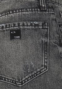 Shorts de mezclilla negra con un acabado desgastado, diseño de cinco bolsillos y etiqueta en el bolsillo trasero con el logo de la marca. Tejido texturizado con detalles de costura.