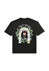 Maglietta nera con un motivo ad arco floreale bianco decorato con foglie, limoni e fiori rosa, e la scritta "PAS DE MONACO" sopra di esso.