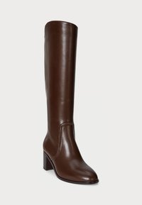 Bota de cuero marrón hasta la rodilla con un diseño estructurado, puntera cuadrada y un tacón apilado. Textura suave con detalles de costura mínimos.