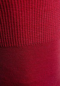 Tessuto a maglia rosso a coste con un motivo testurizzato, caratterizzato da sezioni contrastanti di texture liscia e a coste. Materiale morbido.