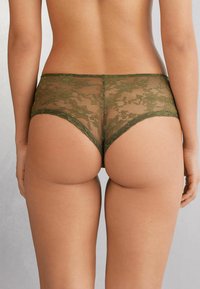 Olive green lace hipster underwear with floral pattern, sheer material, and smooth edges. High-waisted design enhances comfort and fit.