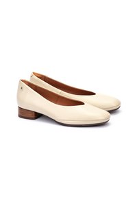 Bailarinas de cuero beige con punta redondeada, diseño minimalista, tacón de madera y detalle del logo lateral. Textura suave con suela interior acolchada.