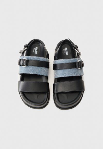 Fekete szandálpár farmer és bőr pántokkal, ezüst csat részletekkel, valamint Moschino Milano logóval a talpban.