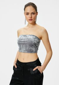 Cropped top strapless in velluto grigio con una texture liscia, caratterizzato da un orlo dritto e un design aderente, abbinato a pantaloni di satin neri.