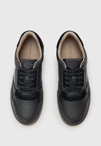 Sneaker neri con una combinazione di pelle liscia e pelle testurizzata, dotati di un design con lacci, punta perforata e rivestimento interno color cuoio.
