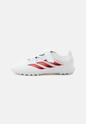Weißer Fußballschuh mit roten und schwarzen Adidas-Streifen, Klettverschluss und strukturierter Sohle für Kunstrasen.
