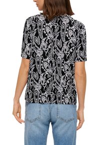 Zwart-witte t-shirt met korte mouwen, versierd met een paisleypatroon en een geribbelde structuur. De achterkant heeft een rechte zoom en een relaxte pasvorm.