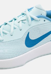 Világoskék sportcipő hálós felsőrésszel, texturált felülettel, fehér középtalppal és sötétkék Swoosh logóval az oldalon. A fűzők is világoskékek.