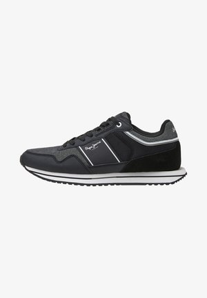 Black athletic shoes with a mix of mesh and suede materials. Features white stripes and branding, flat sole with a textured tread design.