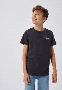 T-shirt en coton noir avec des manches courtes et un col rond, orné d'un petit logo blanc "T.W.S.N." sur la poitrine. Coupe décontractée.