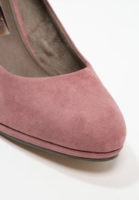 Nahaufnahme eines mauve-farbenen Wildlederschuhs für Frauen mit runder Zehenpartie und gepolstertem Innenfutter auf weißem Hintergrund.