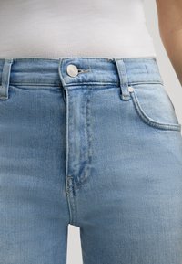 Jasnoniebieskie dżinsy z wysokim stanem, wykonane z denimu, z zapięciem na guziki z srebrnym wykończeniem oraz przednimi kieszeniami z haftowanym wzorem.