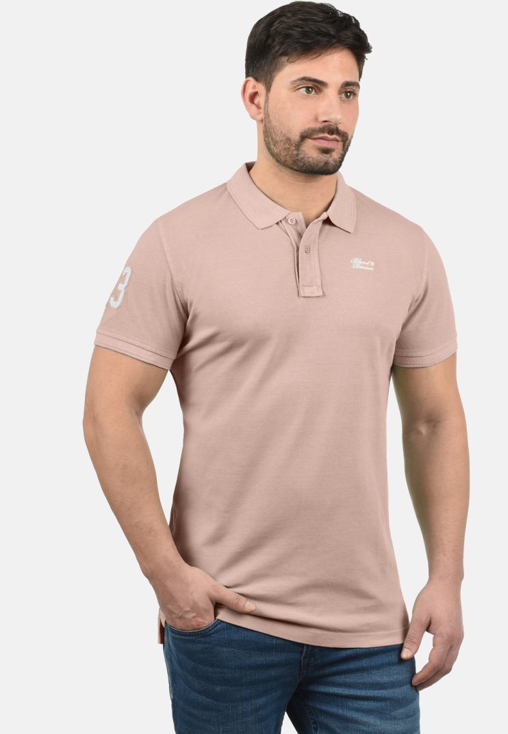 Lichtroze katoenen polo met kraag, een knoopsluiting met twee knopen en een geborduurd logo op de borst. Heeft een nummeraccent op de mouw.