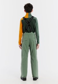 Groen en oranje skikostuum met textuurstof, verstelbare banden met logo, ontspannen pasvorm broek en een ontwerp met hoge kraag.