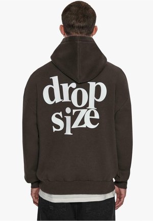 Dunkelbrauner Kapuzenpullover mit großem weißen Text "drop size" auf der Rückseite. Weicher Stoff, Kapuzenentwurf, gerippte Bündchen und Saum.