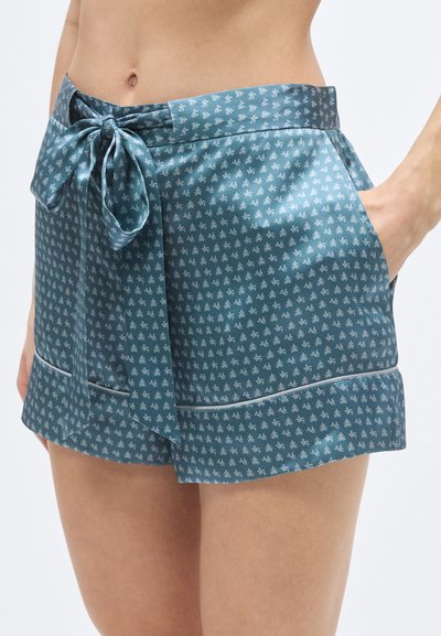 Tűrkiz rövidnadrág apró, ismétlődő virágmintával, szaténszerű anyagból készült. Kötős derékrésszel és oldalzsebekkel rendelkezik.