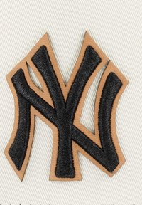 Logo der New York Yankees; schwarzes, gesticktes "NY" auf einem sandfarbenen Lederhintergrund; strukturierte Details; kantiges Design.