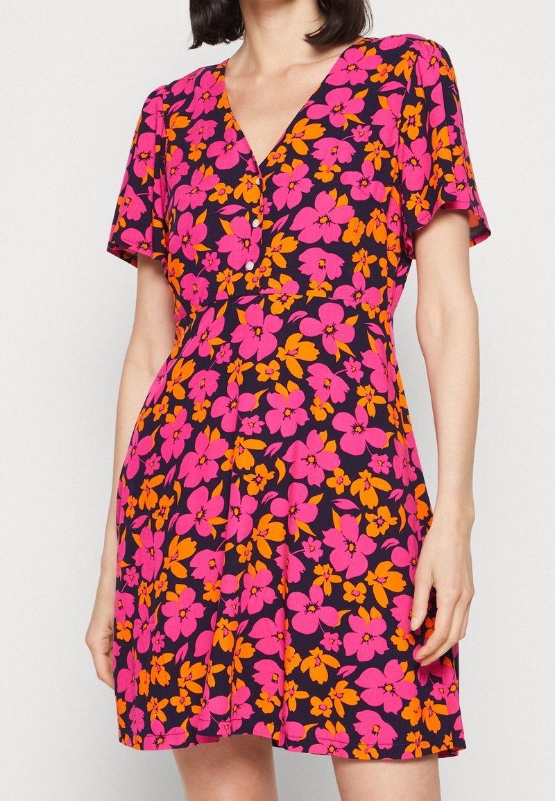 Kwiatowa sukienka w granatowym kolorze z żywymi różowymi i pomarańczowymi kwiatami. Krótkie rękawy, dekolt w kształcie litery V oraz detale z guzikami z przodu. Miękka tkanina.