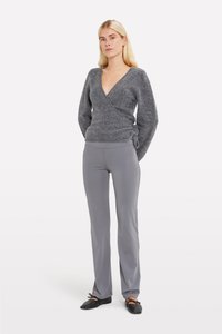 Gray knit wrap sweater with a deep V-neck and long sleeves, paired with slim-fit gray pants and black flat shoes.