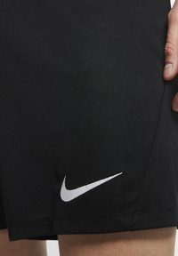 Pantalones cortos deportivos negros de Nike con una textura suave, un diseño ajustado y un logo blanco prominente en el dobladillo.