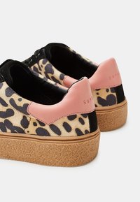 Sneaker con stampa leopardata, con una parte superiore texturizzata nera e beige, dettagli rosa sul tallone e una suola piattaforma in sughero naturale.