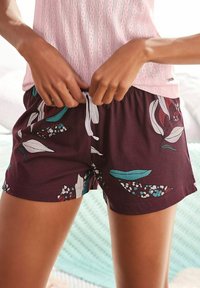 Donker bordeauxrode shorts met een bloemmotief in aqua en wit. Elastische tailleband met een witte trekkoord. Zachte katoenstof.