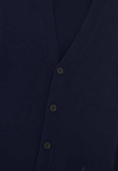 Cardigan bleu marine en laine douce, avec un col en V, six boutons noirs, et une surface texturée avec un logo en bas.