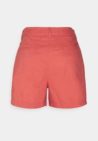 Shorts en lin de couleur corail avec une coupe ajustée, dotés de poches arrière et d'une texture lisse, de bords ourlés et d'une taille standard.