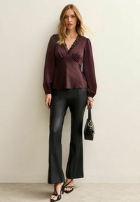 Burgundy sidentopp med spetsdetaljer, lång ärm och V-ringning, kombinerad med svarta byxor i faux läder med vid ben och en minimalistisk svart handväska.