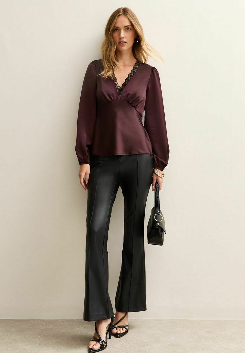Burgundy sidentopp med spetsdetaljer, lång ärm och V-ringning, kombinerad med svarta byxor i faux läder med vid ben och en minimalistisk svart handväska.