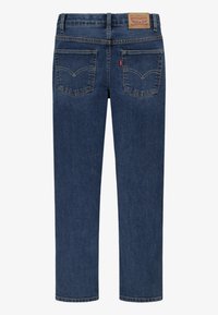 Dark blue denim jeans with a straight leg design, featuring two back pockets, stitching details, and a branded leather patch at the waist.