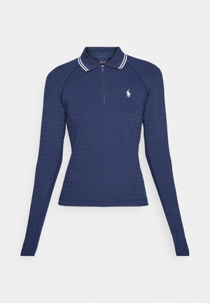 Polo de manga larga en color navy con un diseño texturizado, cuello con cremallera y cuello a rayas blancas. Presenta un pequeño logo bordado en el pecho.