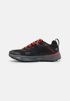 Zapatilla deportiva negra con acentos naranjas, parte superior texturizada y suela acolchada gris, que cuenta con una resistente suela externa con tracción.