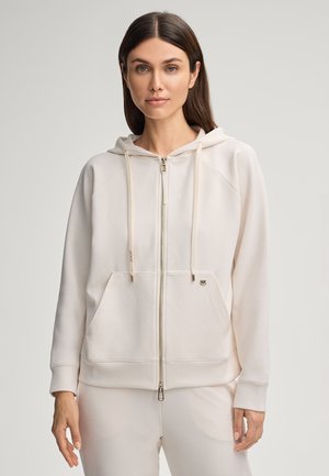 Lichtbeige rits hoodie met een kangoeroezak, een capuchon met trekkoord en geribbelde manchetten. Bevat een logo-detail op de linkerborst. Glad van textuur.