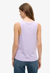 Lila mouwloze tanktop met een ronde halslijn; zachte katoenmix stof; gebogen zoom; gecombineerd met hoge taille blauwe jeans.