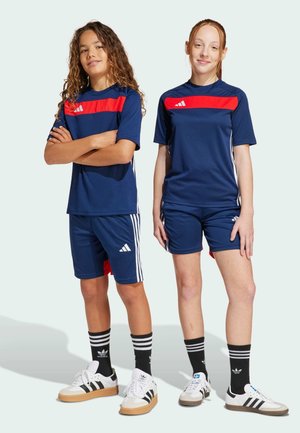 Marine sportuniformen met rode horizontale strepen, met het Adidas-logo. Ontworpen met shorts, gecombineerd met zwarte gestreepte sokken en sneakers.