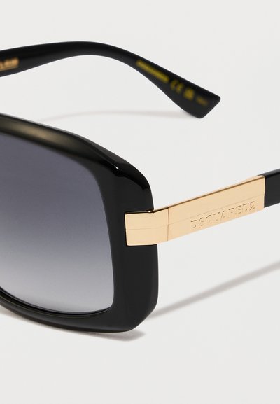 Occhiali da sole rettangolari neri e oro con lenti grigie sfumate, con "DSQUARED2" inciso sul braccio dorato.