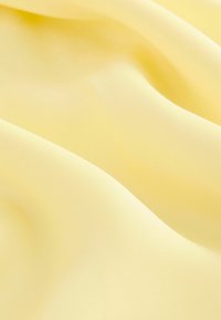 Tissu jaune clair avec une texture lisse et légèrement brillante, exhibant de douces drapés et plis, idéal pour créer des vêtements ou des articles de décoration.