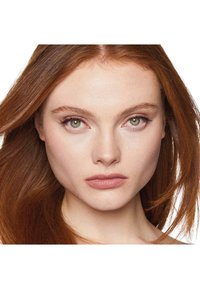 Primo piano di una persona con lunghi capelli lisci castano-rossi, occhi verdi e trucco naturale. Le caratteristiche includono pelle liscia e labbra piene.