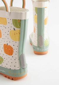 Bottes de pluie à motifs de citrouille avec une base blanche, des accents verts et des semelles orange. Caoutchouc texturé avec de mignonnes illustrations de citrouille et des pois.